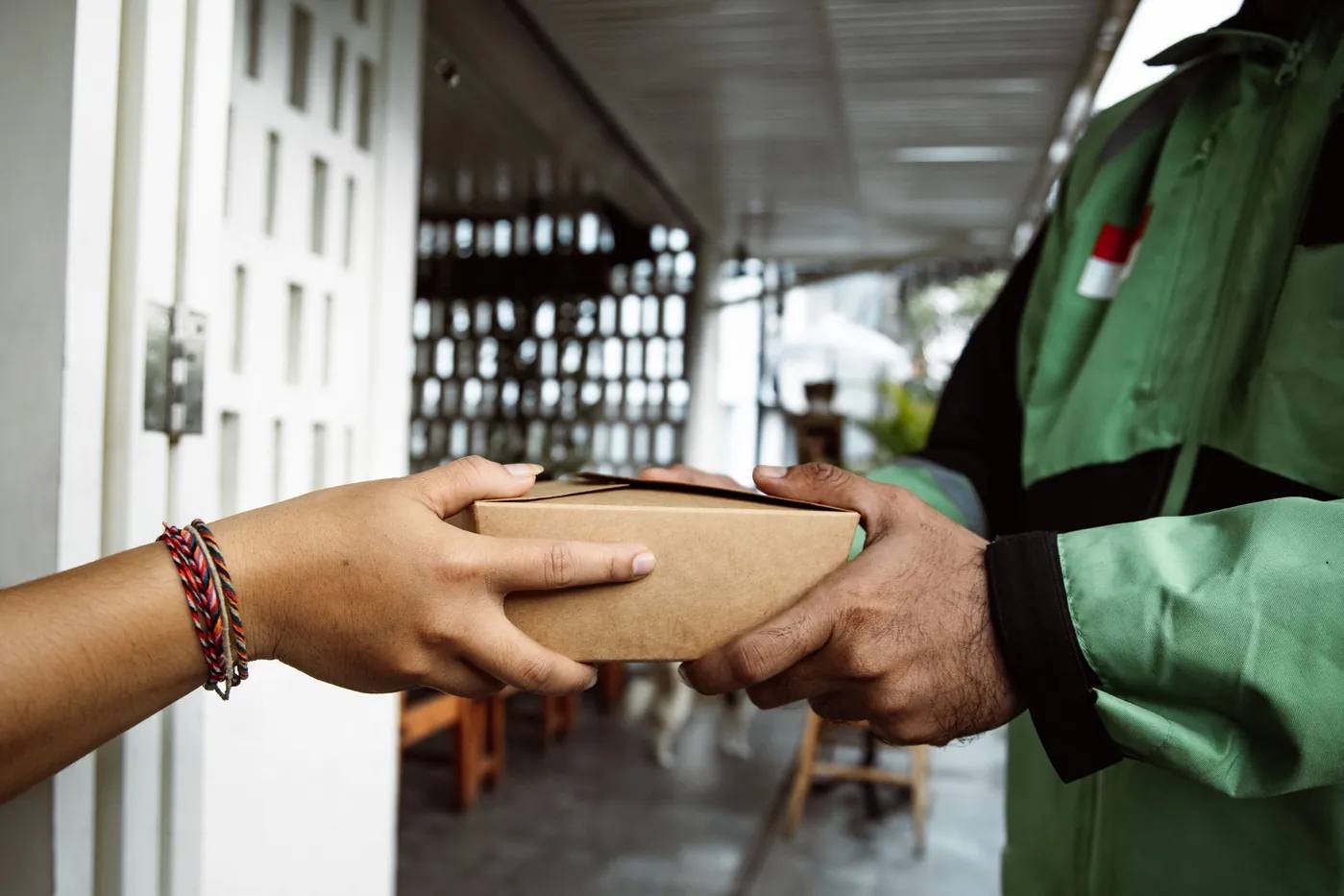 Courier hand delivering a brown paper parcel to a customer at the door