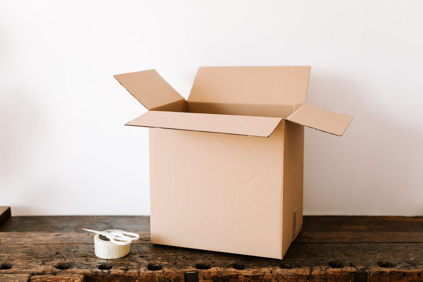 Sealed cardboard shipping box with packing tape and scissors on a dark wooden table